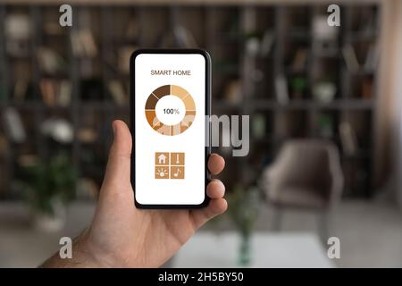 Closeup man holding cellphone with smart home application on screen. Stock Photo