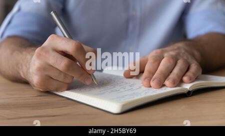 Young man handwriting notes in paper planner. Stock Photo
