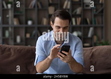 Smiling young man enjoying using mobile application. Stock Photo