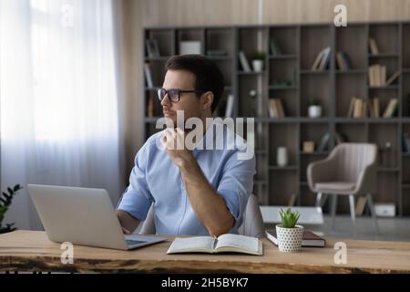 Thoughtful young businessman in eyewear looking in distance. Stock Photo