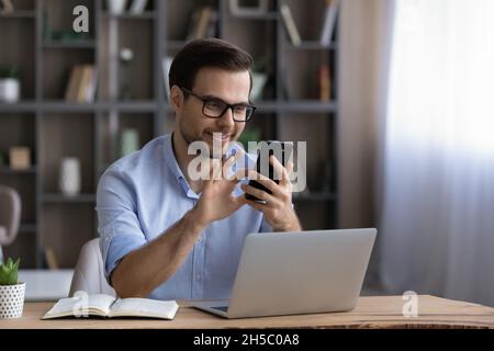 Happy handsome young man using cellphone in office. Stock Photo