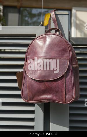 burgundy leather backpack on the metal fence Stock Photo