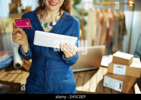 Closeup on small business owner woman with tablet PC and credit card in the office. Stock Photo