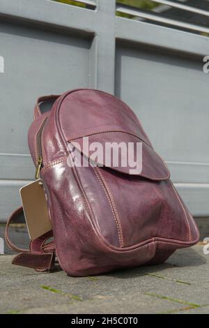 burgundy leather backpack on the metal fence Stock Photo