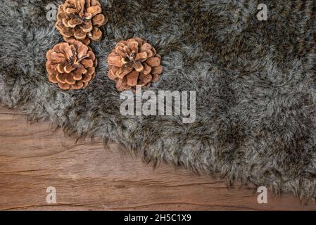 Fluffy fur plaid and pine cones on wood. Stock Photo