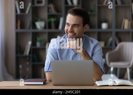Distracted from computer work young businessman looking in distance. Stock Photo