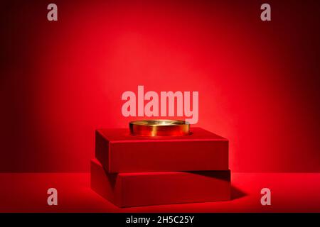 Empty red podium made of gift boxes and golden circle and decor on a red background. Pedestal, showcase for products and cosmetics. Chinese New Year c Stock Photo