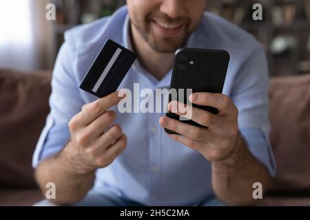 Close up man holding credit card and phone in hands. Stock Photo