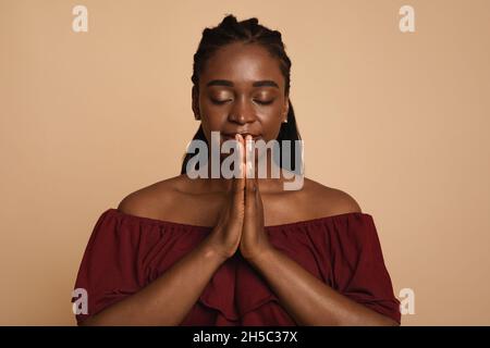 Delighted african american woman praying with closed eyes Stock Photo