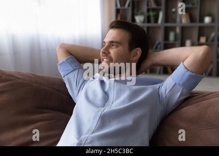 Relaxed young man lying on comfortable sofa. Stock Photo