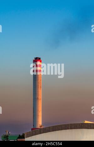 Large factory chimney fuming at dusk. Stock Photo