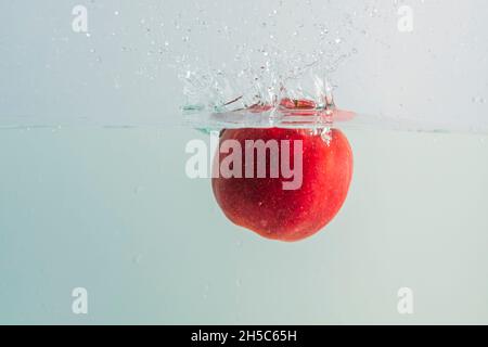 Close up view of red apples  falling in water on background. Stock Photo