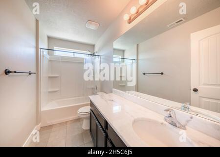 Interior of a white bathroom with black bathroom fixtures and light gray tiles flooring Stock Photo