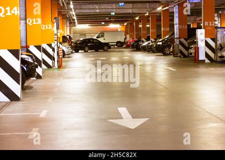 Modern parking for cars in a mall, supermarket. Internal underground parking for lots of automobiles. Markings on a road, indicating with an arrow a r Stock Photo