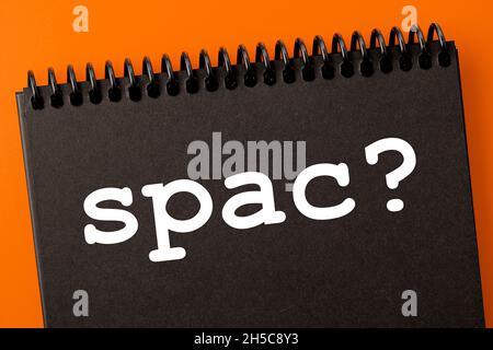 spac (special purpose acquisition company) theme. spak? inscription in an open black notebook, on an orange background Stock Photo