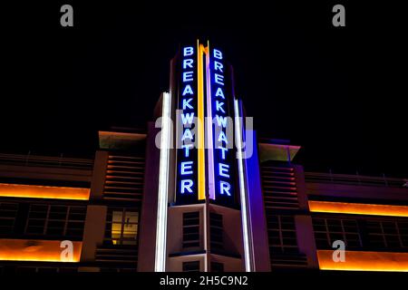 Miami Beach, USA - January 20, 2021: Looking up low angle view on art deco district at night with neon blue light sign of Breakwater Hotel facade in S Stock Photo