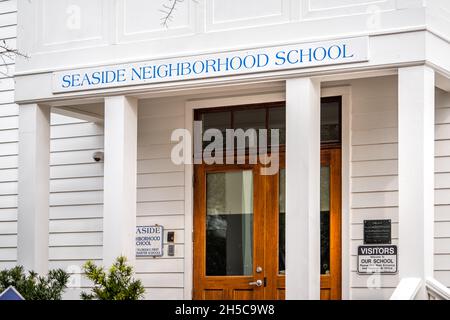 Seaside, USA - January 10, 2021: White wooden house building cottage architecture in Florida beach town with Seaside Neighborhood charter school sign Stock Photo