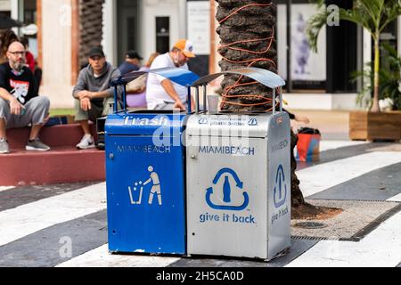 Miami Beach, USA - January 17, 2021: Famous Lincoln road shopping street with people on sidewalk and blue recycle trash garbage bins Stock Photo