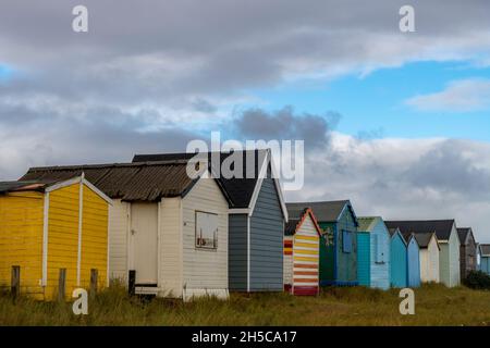 row of beach huts at heacham on the north norfolk coast, atmospheric line or terrace of beach huts at heacham under a moody sky, homes by the sea. Stock Photo