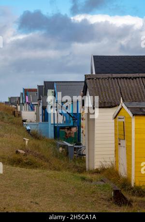 row of beach huts at heacham on the north norfolk coast, atmospheric line or terrace of beach huts at heacham under a moody sky, homes by the sea. Stock Photo