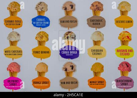 a sign or advertising board showing a number of different flavours of ice creams, seaside holiday treats lollies and ices advertising banner. Stock Photo