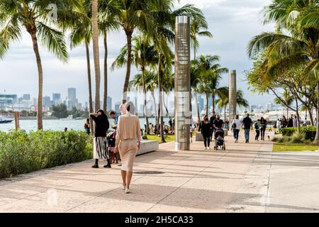 Miami Beach, USA - January 17, 2021: South Pointe park promenade sidewalk with people walking in South Beach, Florida by bay water city view Stock Photo