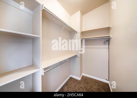 Empty walk in closet of a new home with shelves and metal rods for