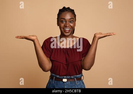 Confused african american woman holding something invisible on both palms Stock Photo