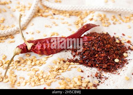Dried red peppers, chili flakes and pepper seeds on burlap. Natural spice concept. Stock Photo