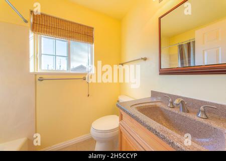 Small yellow bathroom interior with bamboo curtain on the window Stock Photo