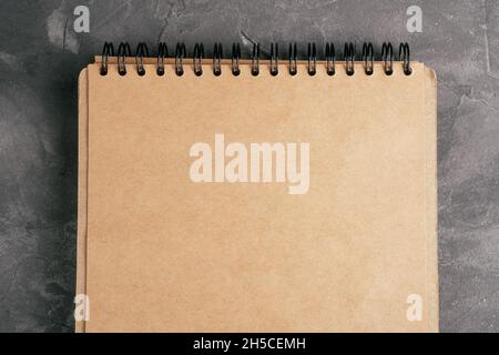 Opened brown kraft paper notebook on spring on gray concrete surface. Top view. Copy space Stock Photo