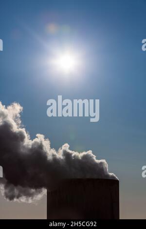 Climate change environmental pollution global warming concept smoke or steam coming out of chimney stack under the sun in a blue sky Stock Photo