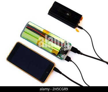 Charging the flashlight and phone through the disassembled Power Bank. Disassemble and test the operation of the portable battery device. Stock Photo