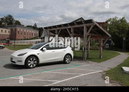 Tesla car at a public electric vehicle charging station in Middlebury, Vermont, USA. The charging station has south facing solar panels overhead the t Stock Photo