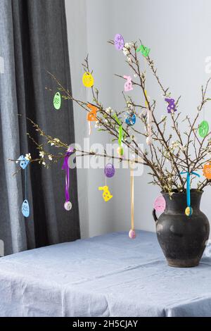 Blooming cherry branches decorated with colorful ribbons with easter eggs, Happy Easter, table setting Stock Photo