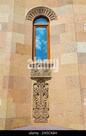 Religious ornament with carved into volcanic tuff stones located on the wall with rectangular window Stock Photo
