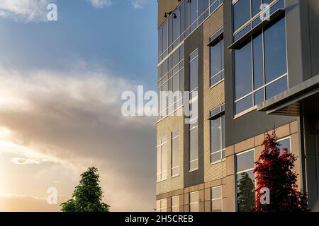 Building facade with bricks, glass and concrete wall cladding during sunset Stock Photo