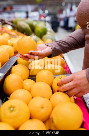 Young woman buying oranges in a supermarket. Stock Photo