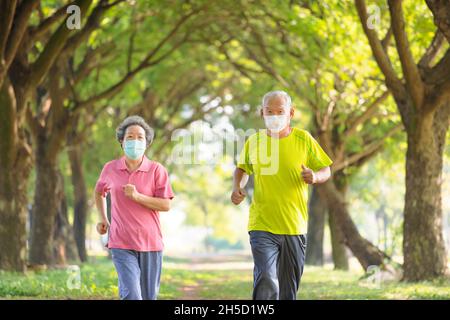 Senior couple wearing face mask and jogging in the park Stock Photo