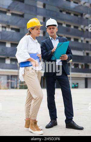 Two young successful architects on the construction site, discuss the construction plan Stock Photo