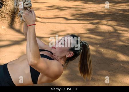42 years old Brazilian training biceps and back using a rope (side view). Stock Photo