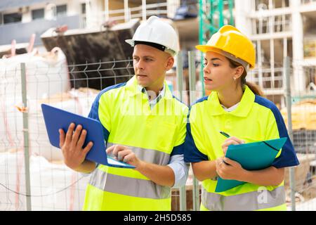 Two engineers are discussing an important project, holding a laptop and an estimate Stock Photo