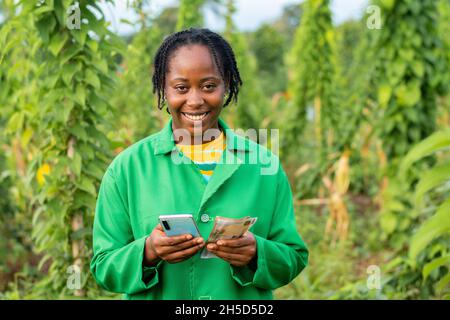 Successful African farmer calculating her income on the phone calculator Stock Photo