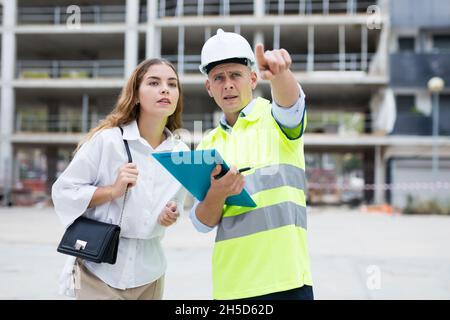Builder talking with client at construction site Stock Photo