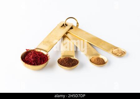 Measuring spoons filled with various spices against a white background. Stock Photo