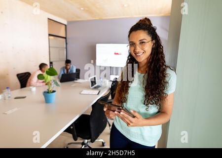 Portrait of confident biracial businesswoman in casuals using tablet pc in creative office Stock Photo