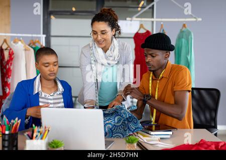 Multiracial male and female fashion designers discussing over patterned fabric at desk in office Stock Photo