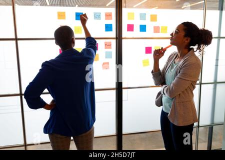 Multiracial businesswomen brainstorming over colorful sticky notes in creative office Stock Photo