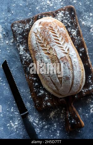 Top down view of a decorated sourdough bread loaf on a wooden board. Stock Photo
