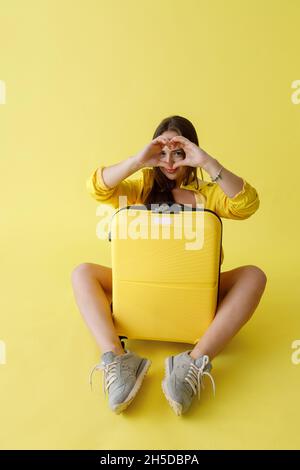 Charming young woman with travel suitcase doing heart sign Stock Photo